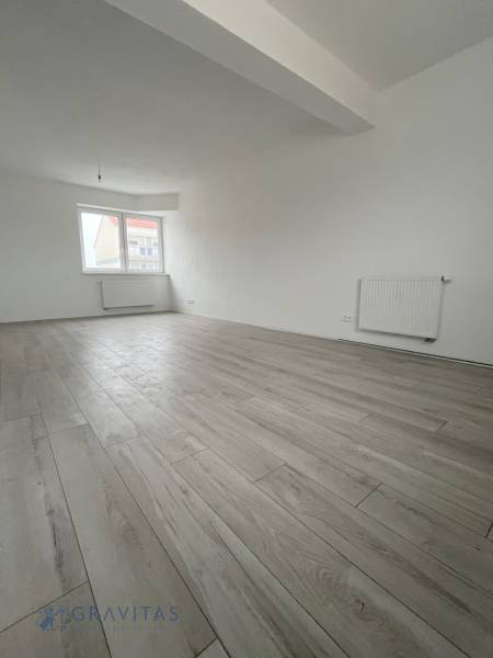 A spacious room with a wooden decor floor in a 2-room apartment.