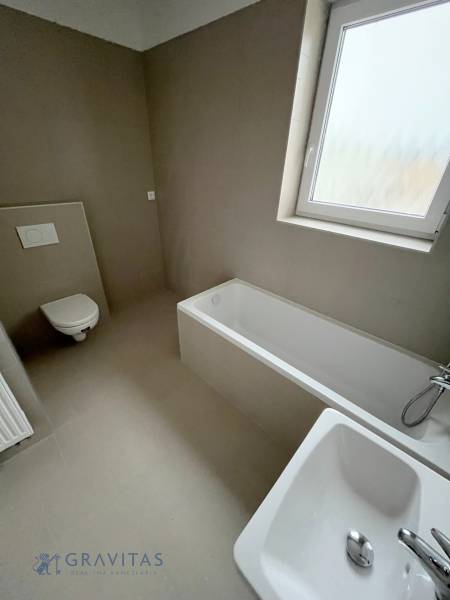 Bathroom in a 2-room apartment with a bathtub, sink, toilet, and a window with frosted glass.