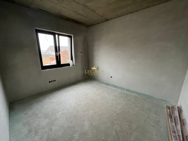 Interior of an empty room in a family house with a window and raw floor.