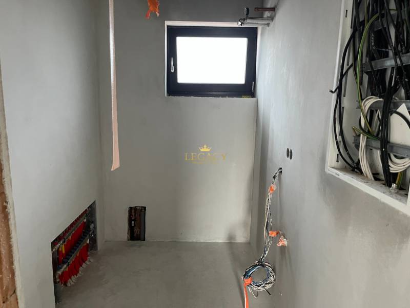 A room in a family house with wiring and a small window, the renovation process is underway.