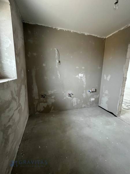 Empty room in a 3-room apartment with unfinished concrete walls and floor.