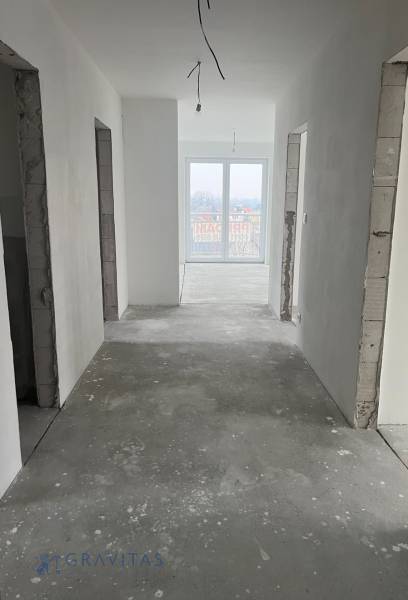 Hallway in a 3-room apartment, white walls, large window, unfinished floor.