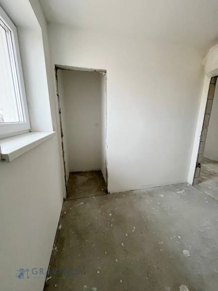 A room in a 3-room apartment with a window, plastered walls, concrete floor, construction modifications.