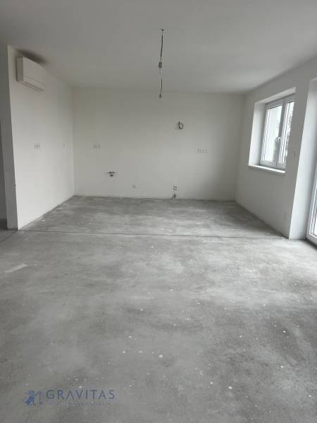 An empty room in a 3-room apartment with a concrete floor and windows.