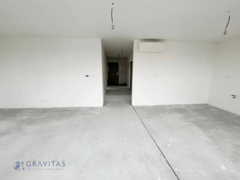 An empty room in a 3-room apartment with a concrete floor and white walls.