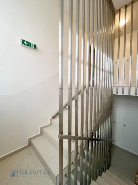 A staircase with a railing and an emergency exit sign in a 2-room apartment.