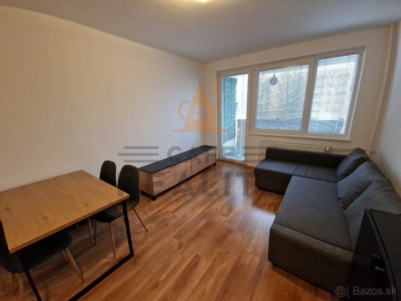 Living room with a corner sofa, dining table, and wooden decor flooring in a 2-room apartment.