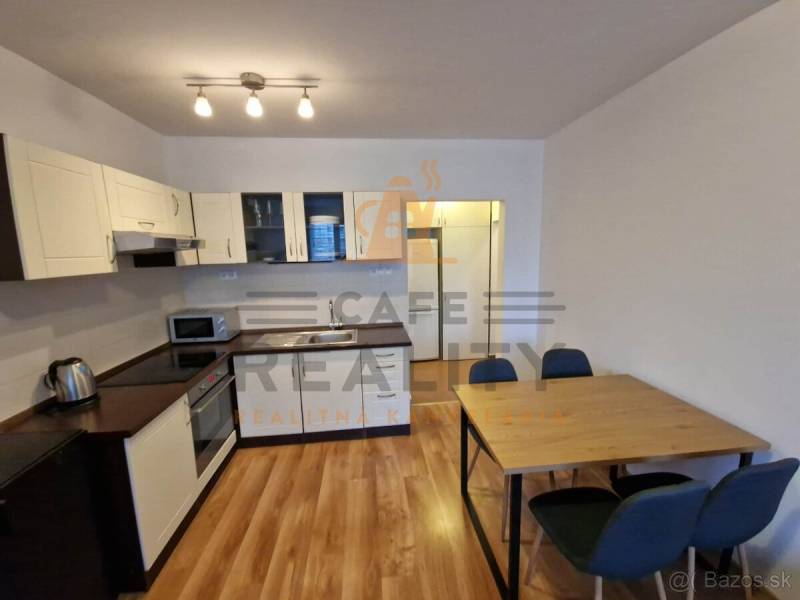 A kitchen in a 2-room apartment with a wooden decor floor, a table with chairs.