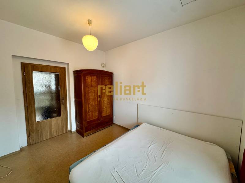 Bedroom in a 2-room apartment with white walls, wooden doors, and a wardrobe.