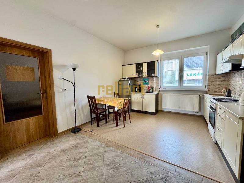 A kitchen in a 2-room apartment with a kitchen table and a floor with a wooden decor.