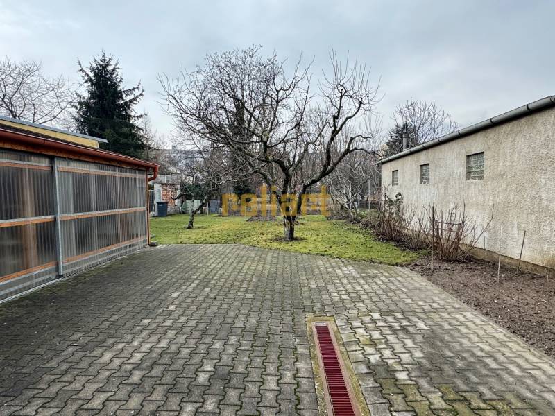 Courtyard by a 2-room apartment on Orieškova Street in Bratislava - Ružinov with trees and paving.