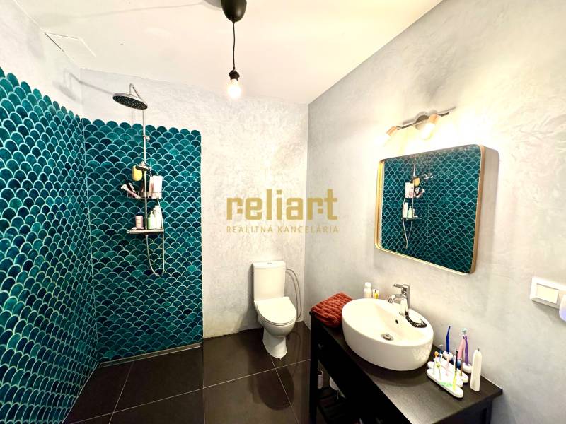 A bathroom with a dark floor and blue tiles in a family house.
