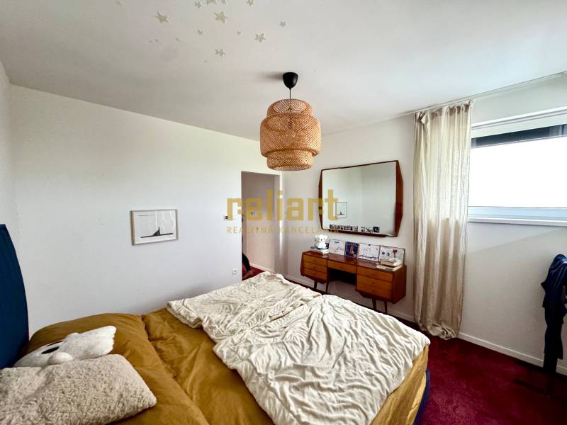 A bedroom in a family house with a bed, a mirror, and a red carpet on the floor.