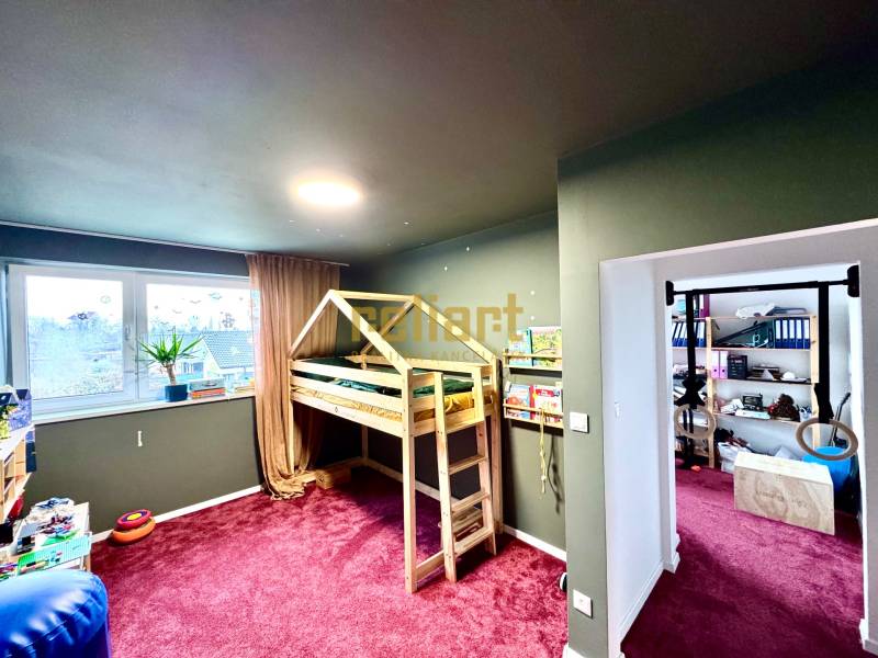 Children's room in a family house with a wooden bed and a burgundy carpet.