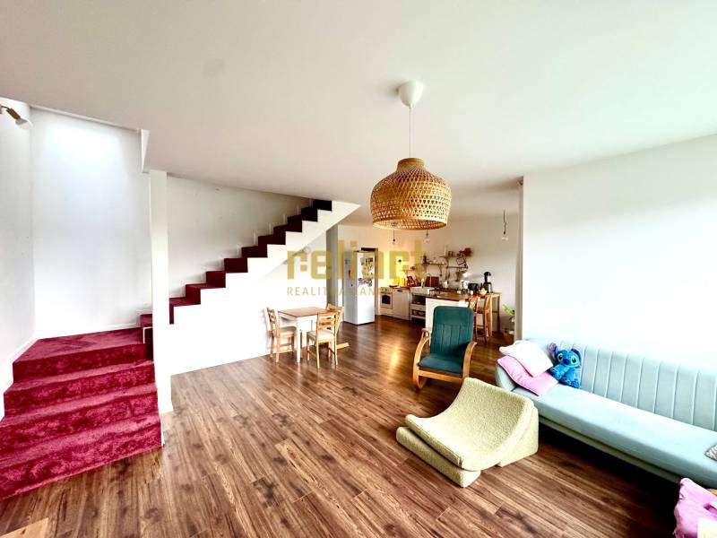 Living room with wood-patterned flooring, staircase, and kitchen in a family house.