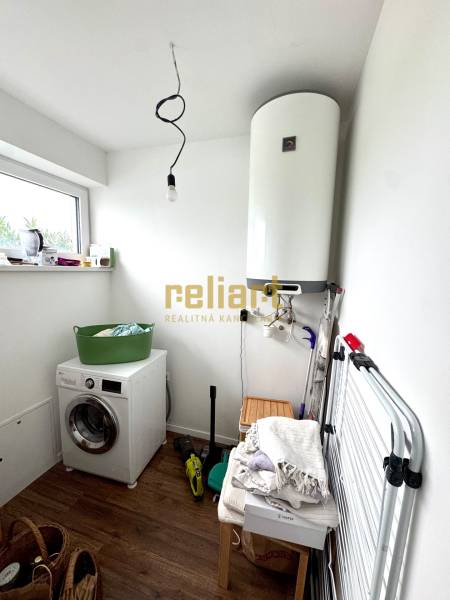 Laundry room in a family house with a washing machine, boiler, and floor with wooden decor.