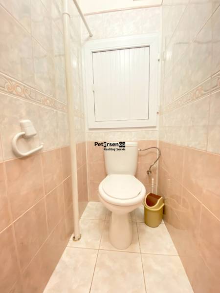 Bathroom in a 2-room apartment with light tiles and a toilet.