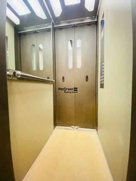 An elevator with metal doors and a mirror, lights on the ceiling.