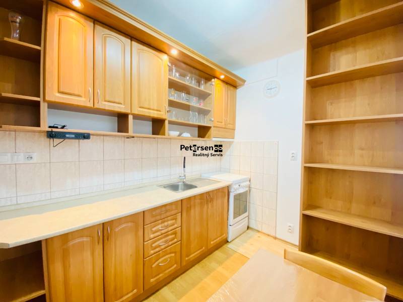 A kitchen in a 2-room apartment with wooden decor furniture and flooring.