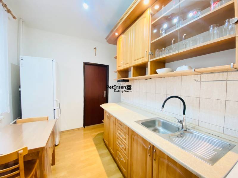 A kitchen in a 2-room apartment with a wooden decor floor and wooden furniture.