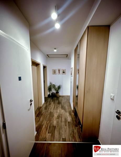 A hallway in a 3-room apartment with a wooden decor floor and built-in wardrobes.