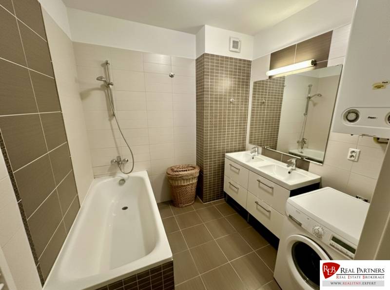 Bathroom with a bathtub, double sink, and washing machine in a 3-room apartment.