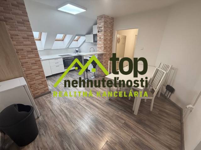 Interior of a one-room apartment with a wooden decor floor and a kitchen with brick cladding.