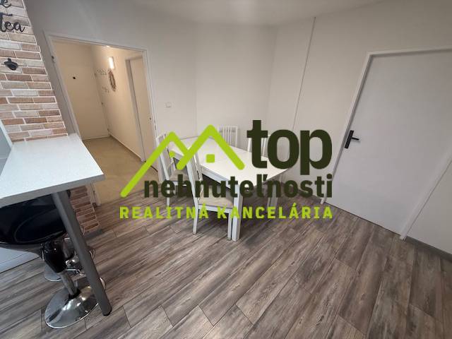 A one-room apartment with a wooden decor floor and a dining table.