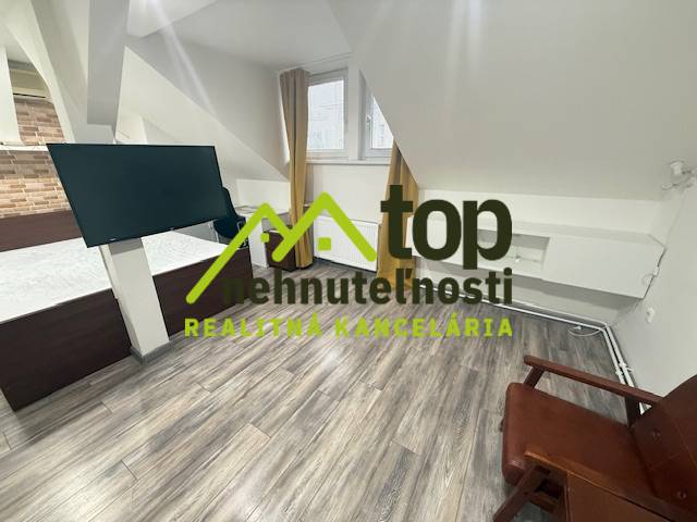 A room with a wooden floor decor, modern television, and furniture in a studio apartment.