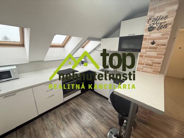 A kitchen area in a studio apartment with a wooden decor floor and skylights.