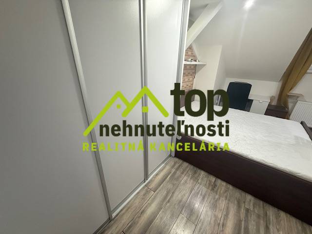 A bedroom in a studio apartment with a wood-patterned floor and a built-in wardrobe.