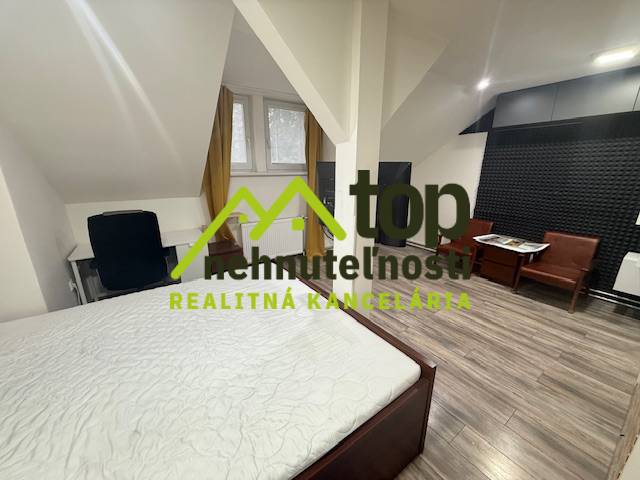 Bedroom in a studio apartment with wood-patterned flooring and a desk.