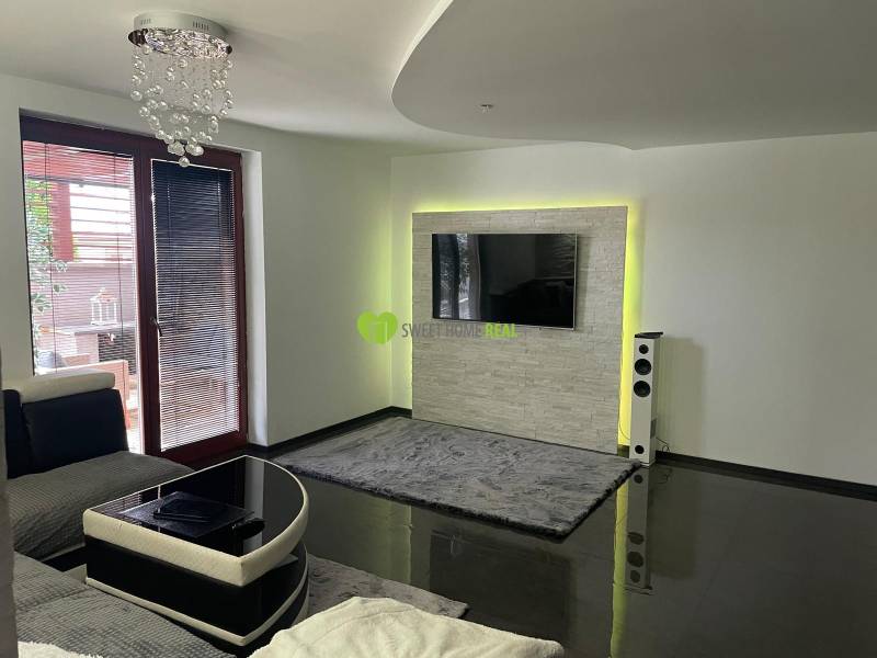Living room in a family house with a glossy floor and a TV on the wall.