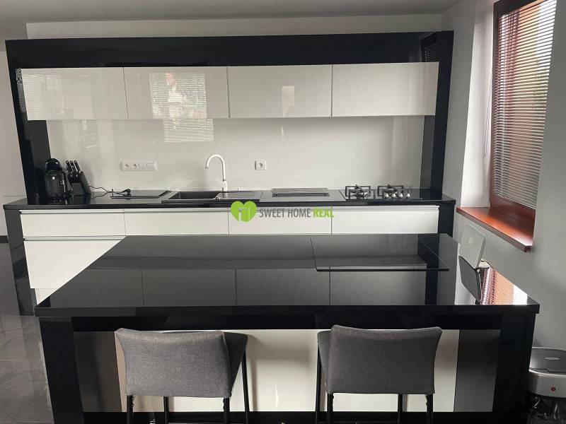 A kitchen in a family house with glossy black and white furniture and a dining counter.