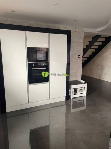 A kitchen in a family house with a glossy black floor and white appliances.