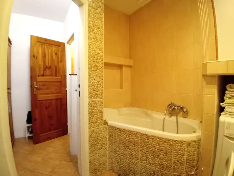 A bathroom in a family house with a bathtub clad in stone tiles and wooden doors.