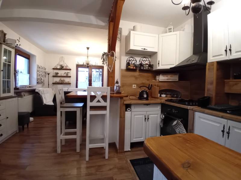 The kitchen and living room in a family house with a wooden decor floor and white furniture.
