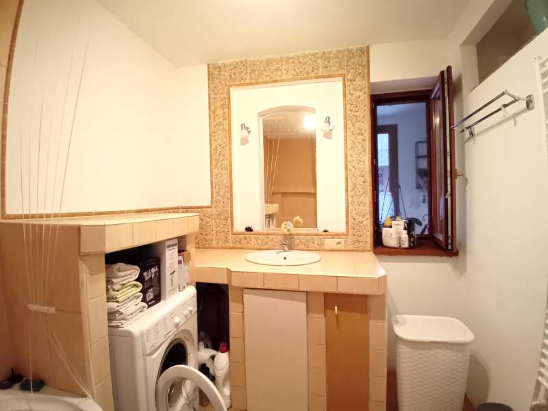 Bathroom of a family house with a washing machine, sink, and open window.