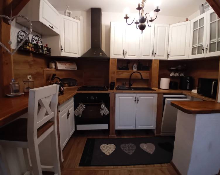 A kitchen in a family house with white cabinets and a wooden decor floor.