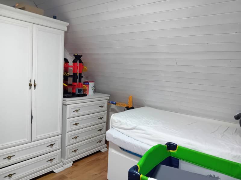 Interior of a family house with a bed, white wardrobe, and floor with wooden decor.
