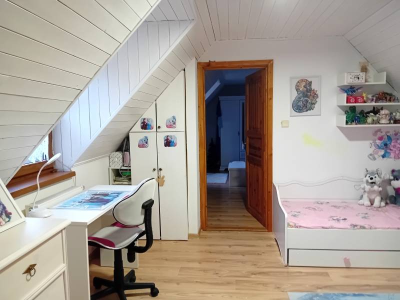 Children's room in a family house with a desk and a bed, floor with wooden decor.