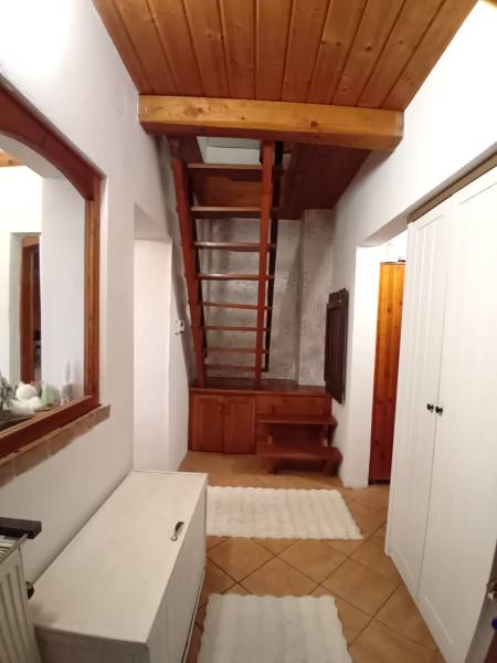 Interior of a family house with a wooden staircase, tiles, and white cabinets.