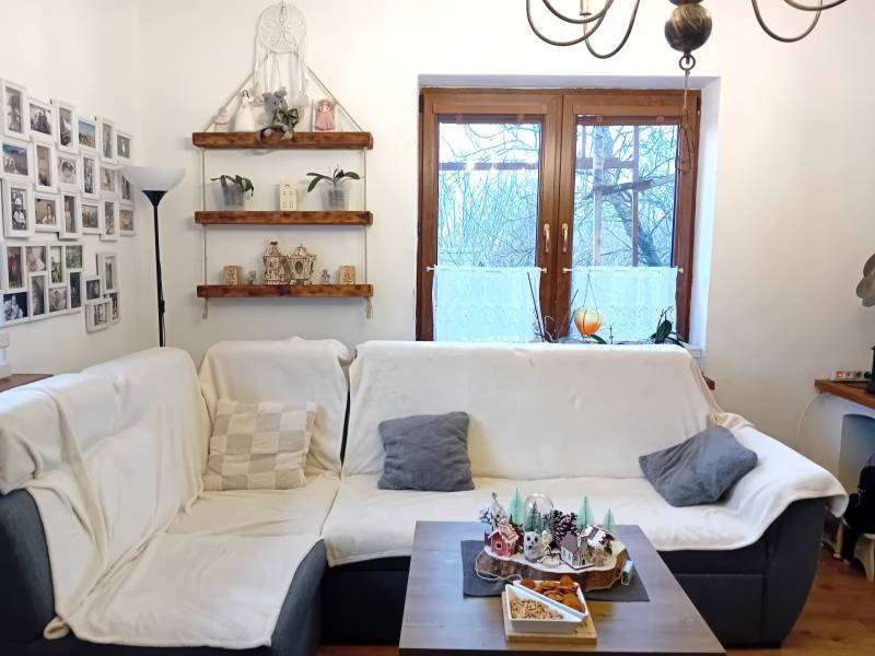 Living room in a family house with a sofa, photo gallery, shelves, and decorations.