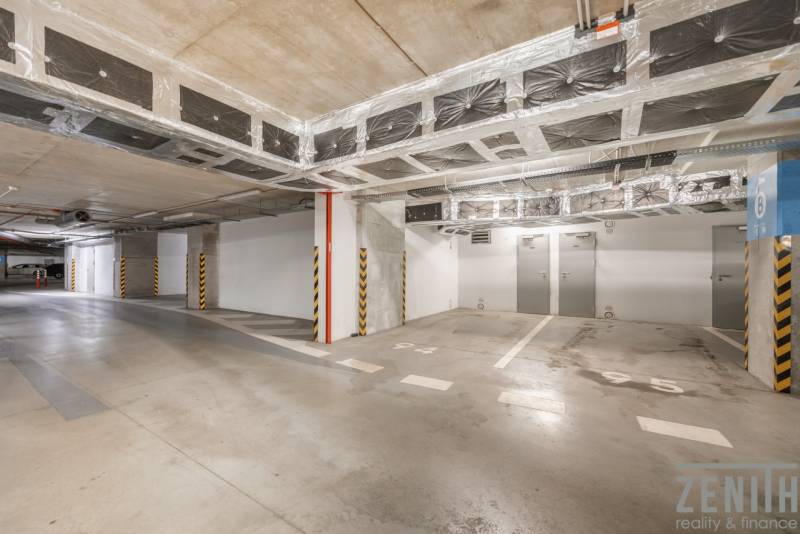 Underground parking lot with available parking spaces, lighting, and concrete surface.