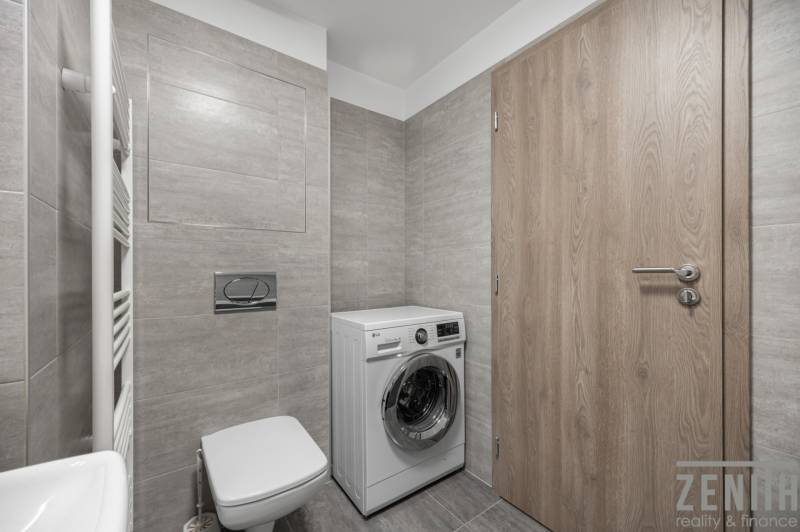 Bathroom with gray tiles, built-in toilet, and washing machine in a 2-room apartment.