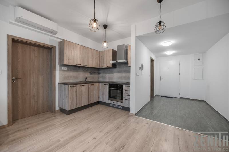 The kitchen of a two-room apartment with a wooden decor floor and built-in lights.
