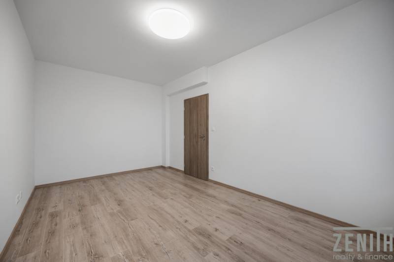 An empty room with wood-patterned flooring in a two-room apartment.