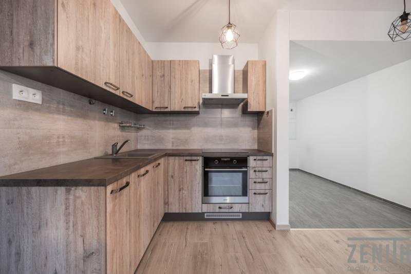 A kitchen in a 2-room apartment with a wooden decor floor, light cabinets, and appliances.