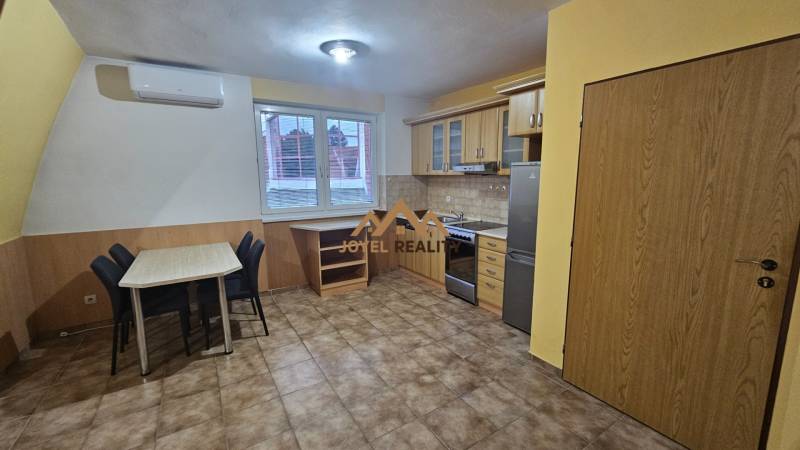 A kitchen in a 3-room apartment with a kitchen unit, dining table, and tiles.