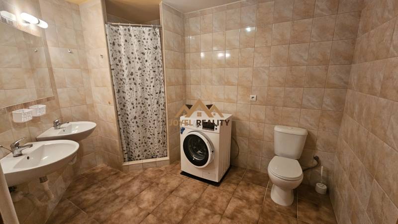 A bathroom in a 3-room apartment with a shower, double sink, toilet, and washing machine.